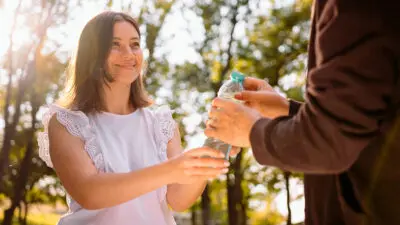 woman giving water to homeless person