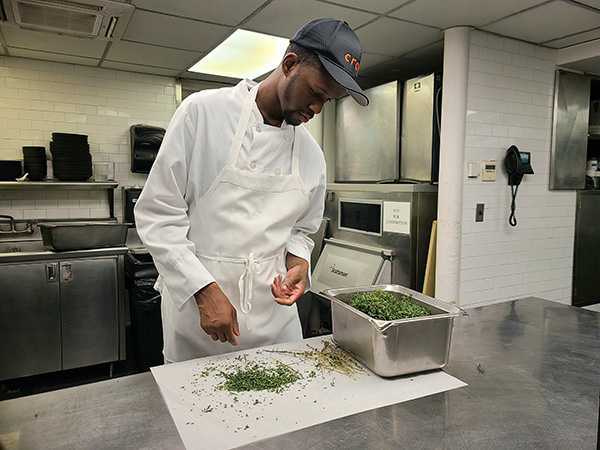 Foto de Manny Irick en la cocina del restaurante.  Fue contratado a través de Smile Farms, que ayuda a crear empleos para personas con discapacidades.