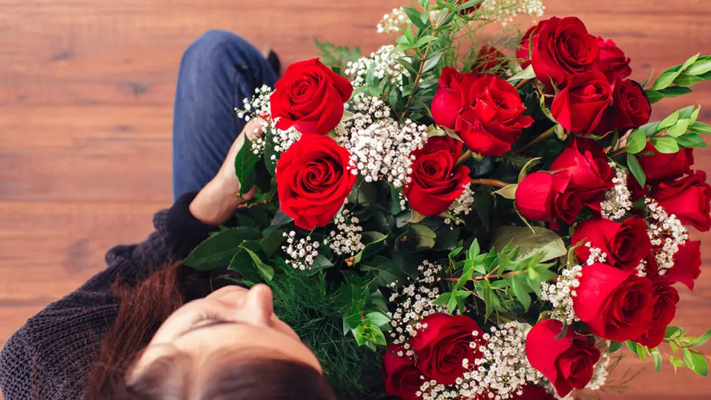 Regalos de cumpleaños para Tauro con una mujer sosteniendo un ramo de rosas