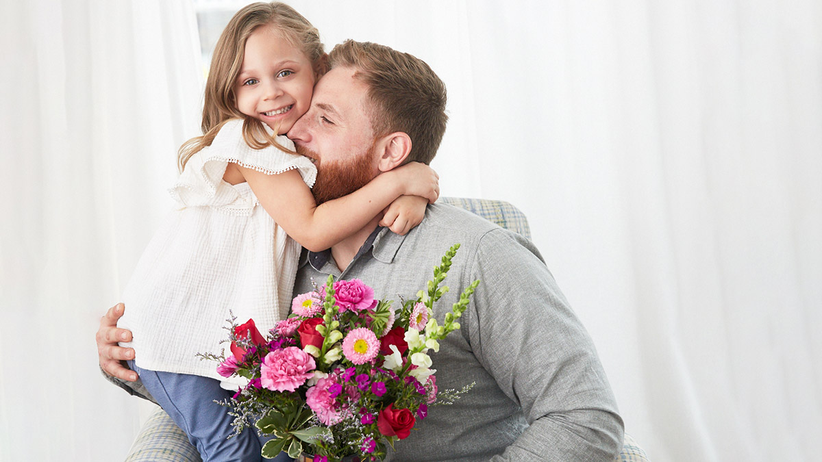 History of mothers day with father and daughter embracing with flowers
