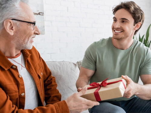 happy man congratulating dad on fathers day and giving him gift