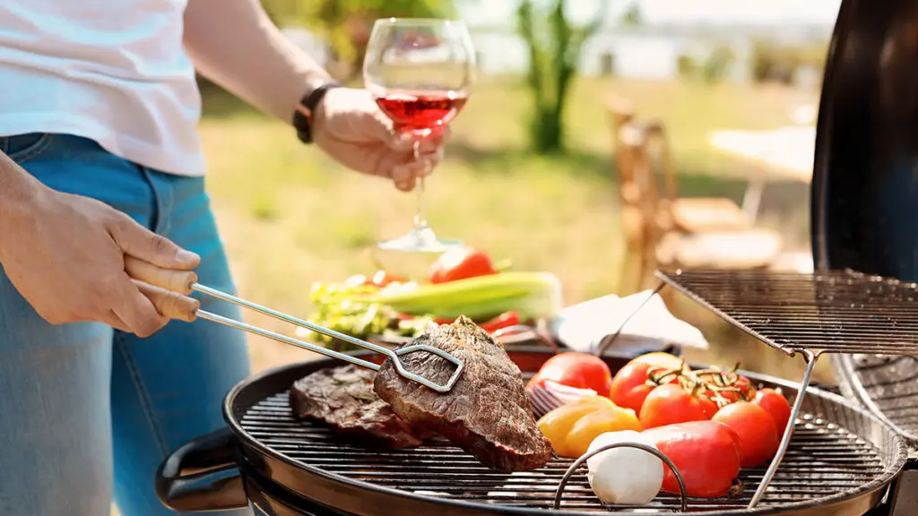 Man cooking meat and vegetables on barbecue grill outdoors