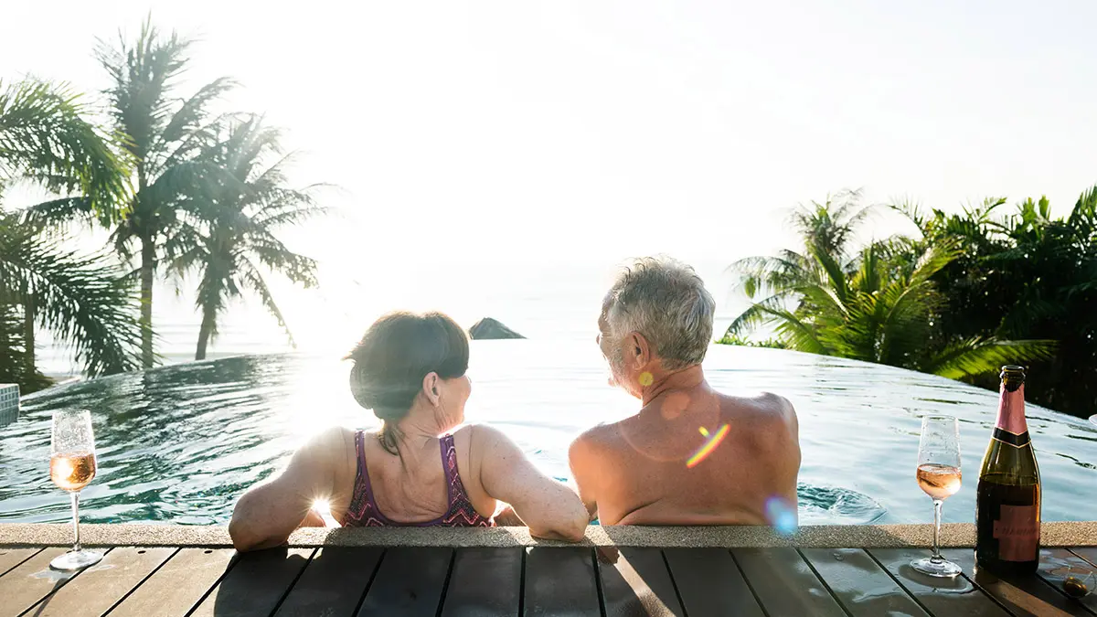 anniversary wishes with senior couple drinking prosecco in a swimming pool