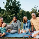 Happy multigeneration family talks while relaxing in backyard.