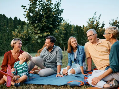 Happy multigeneration family talks while relaxing in backyard.