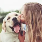 Frame with a beautiful girl with a beautiful dog in a park on green grass.