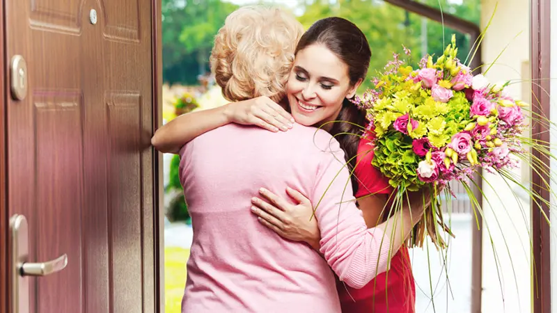 Young woman bringing birthday flowers to her grandmother