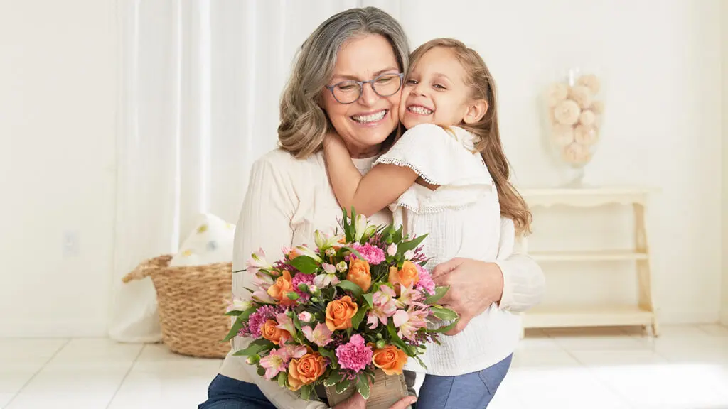 grandparents day grandmother hugging granddaughter with flowers