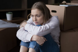 how to declutter with sad woman sitting near heap of cardboard boxes with belongings