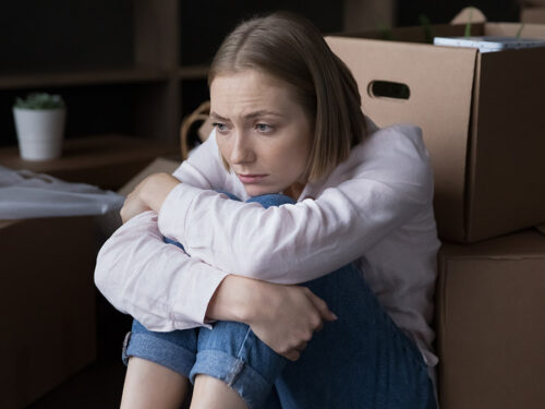 how to declutter with sad woman sitting near heap of cardboard boxes with belongings