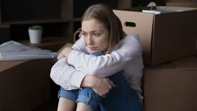 how to declutter with sad woman sitting near heap of cardboard boxes with belongings