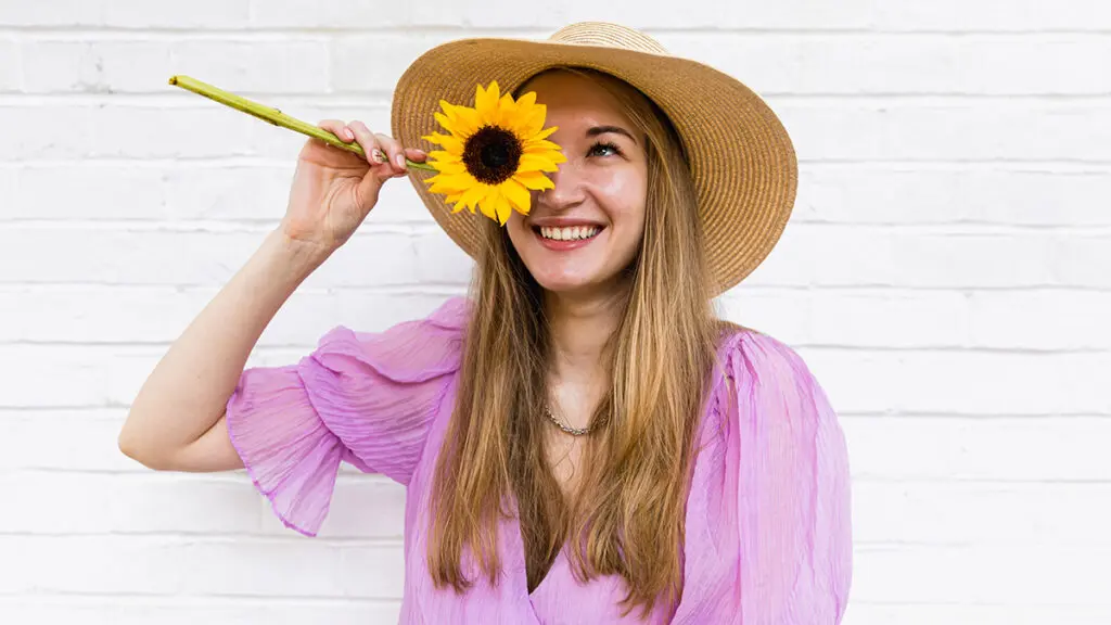 https://www.1800flowers.com/blog/wp-content/uploads/2023/09/sunflower_symbolism_woman_holding_sunflower_in_front_of_face-1024x576.jpg.webp