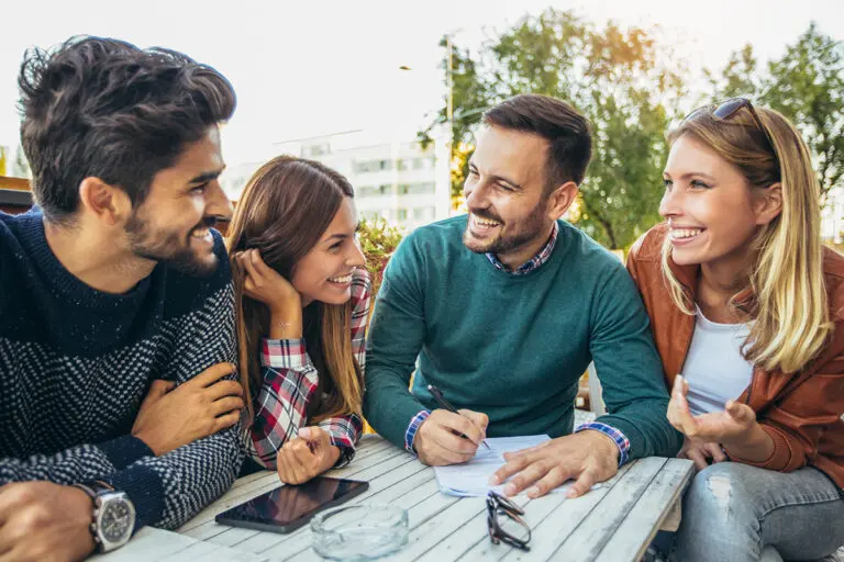 Group of four friends having fun a coffee together. Two women an