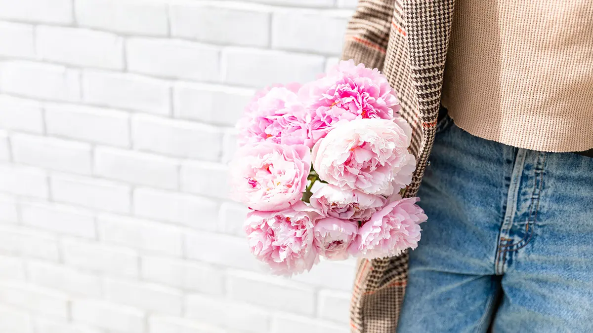 november birth flowers woman holding pink peony bouquet