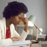 signs of burnout with Frustrated woman keeping eyes closed and massaging nose