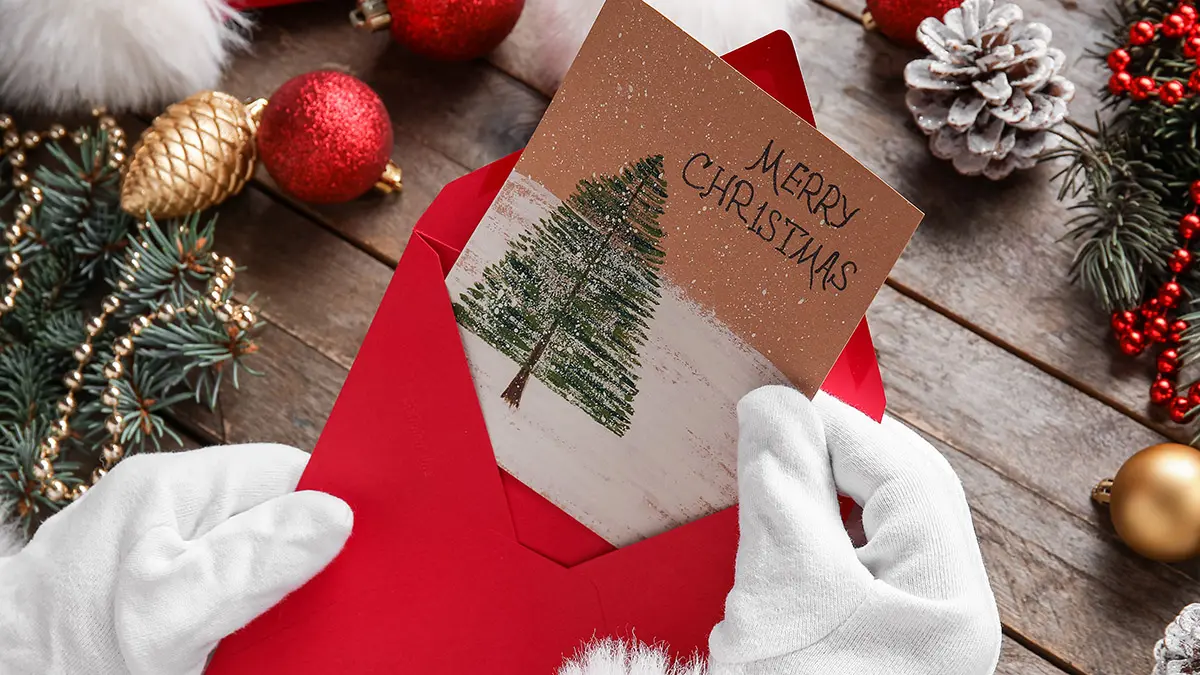 Santa Claus holding envelope with greeting for Merry Christmas a