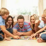 Family Playing Board Game At Home With Grandparents Watching