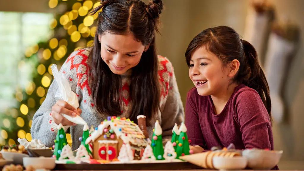 Christmas activities for families with mother and daughter making a gingerbread house