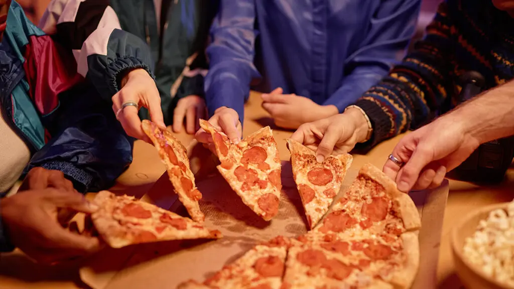 40th birthday ideas with Closeup of diverse group of friends sharing pepperoni pizza at house party