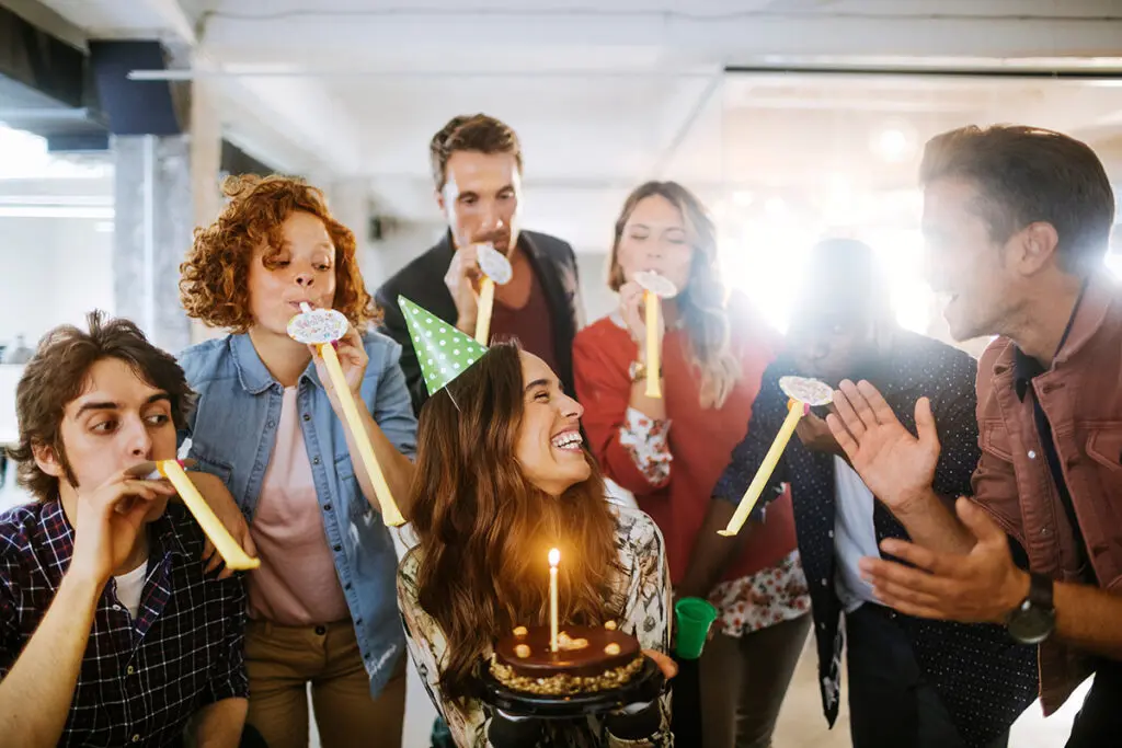 Group of young people celebrating a birthday in the office