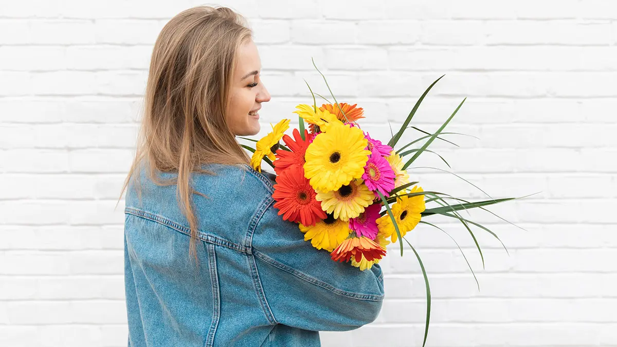 april birth flowers woman holding bouquet of gerbera daisies