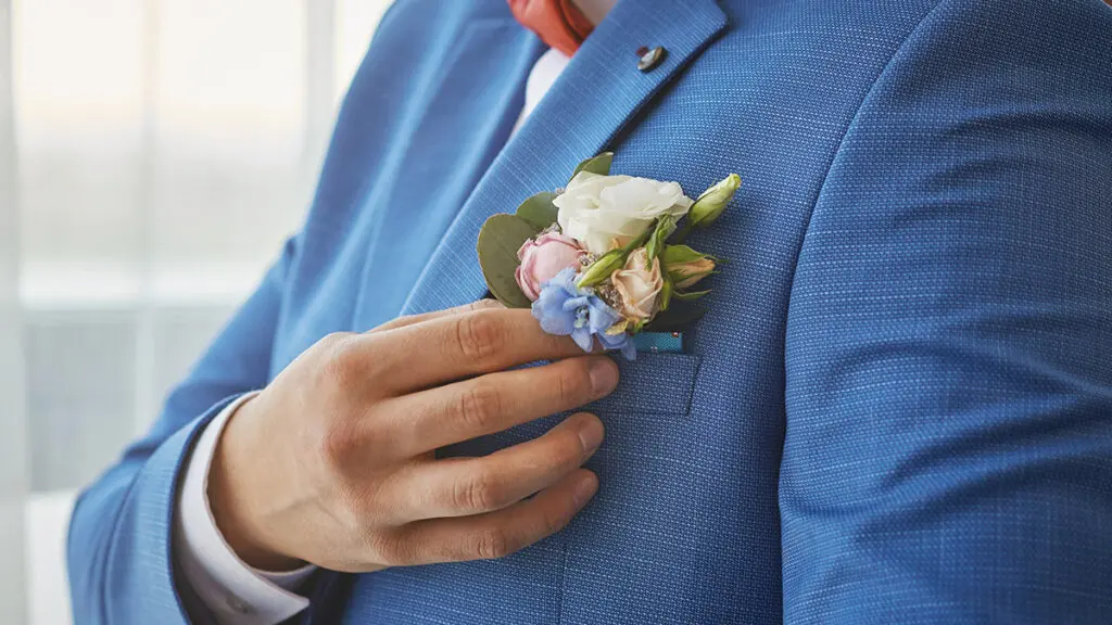bride adjusts the boutonniere on his suit. preparing for the wed