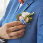 bride adjusts the boutonniere on his suit. preparing for the wed