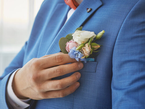 bride adjusts the boutonniere on his suit. preparing for the wed