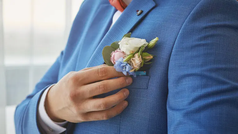 bride adjusts the boutonniere on his suit. preparing for the wed