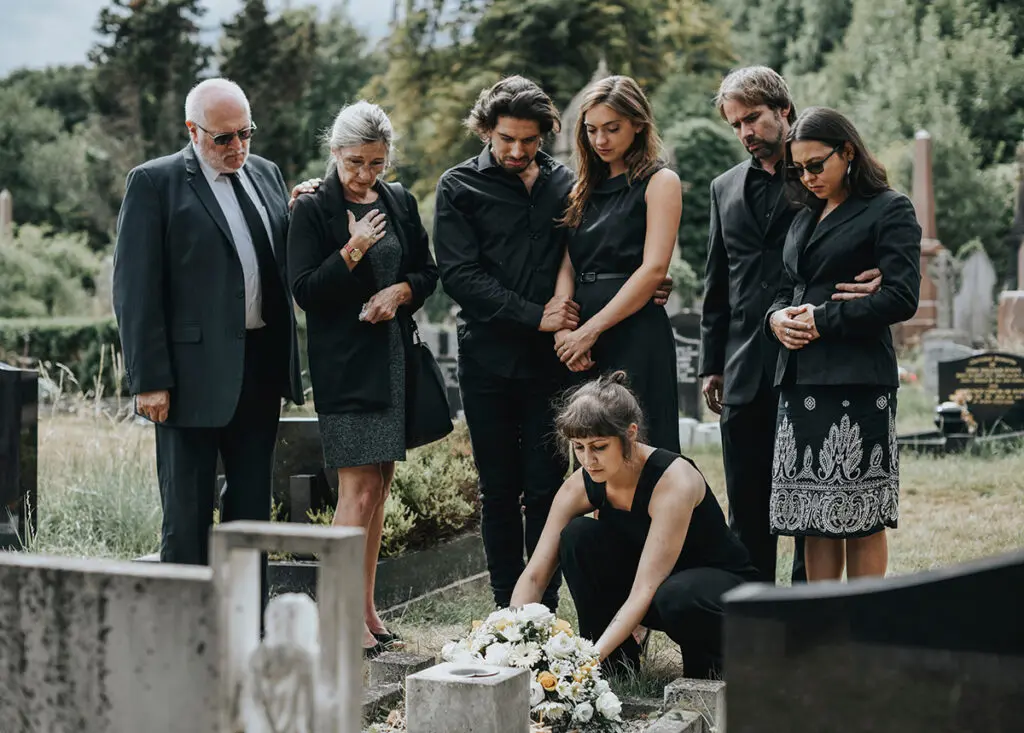Coming Together: The Transformative Power of Funeral Rituals Family laying flowers on the grave