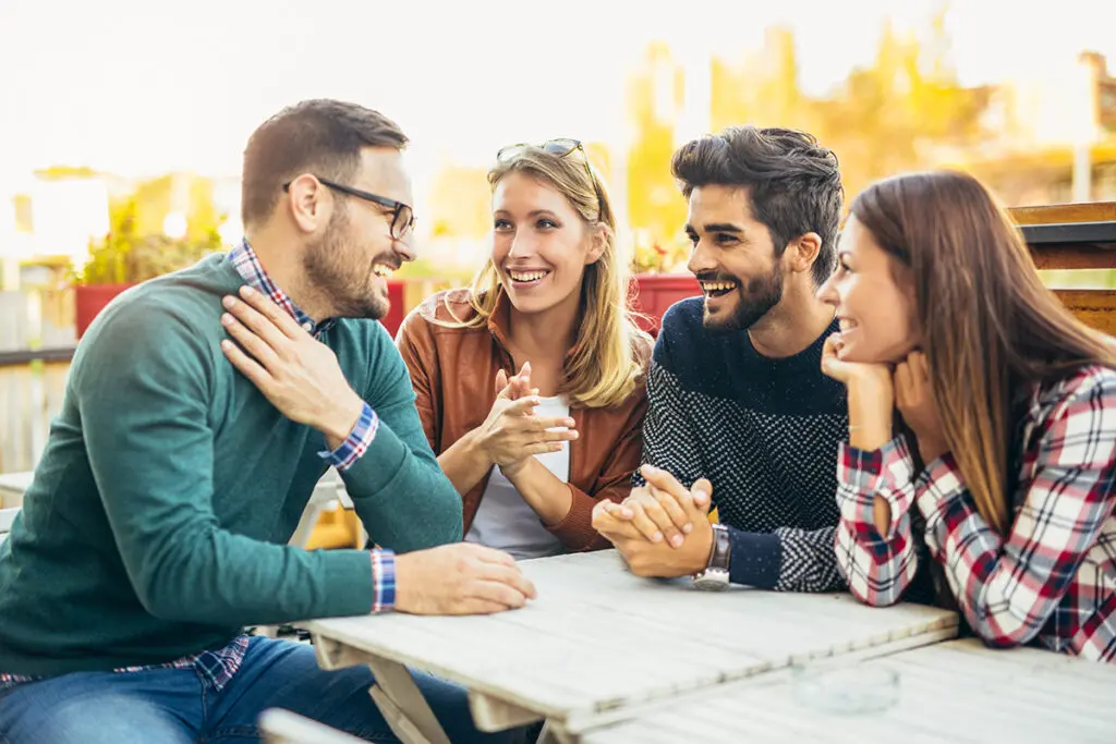 Group of four friends having fun a coffee together. Two women an